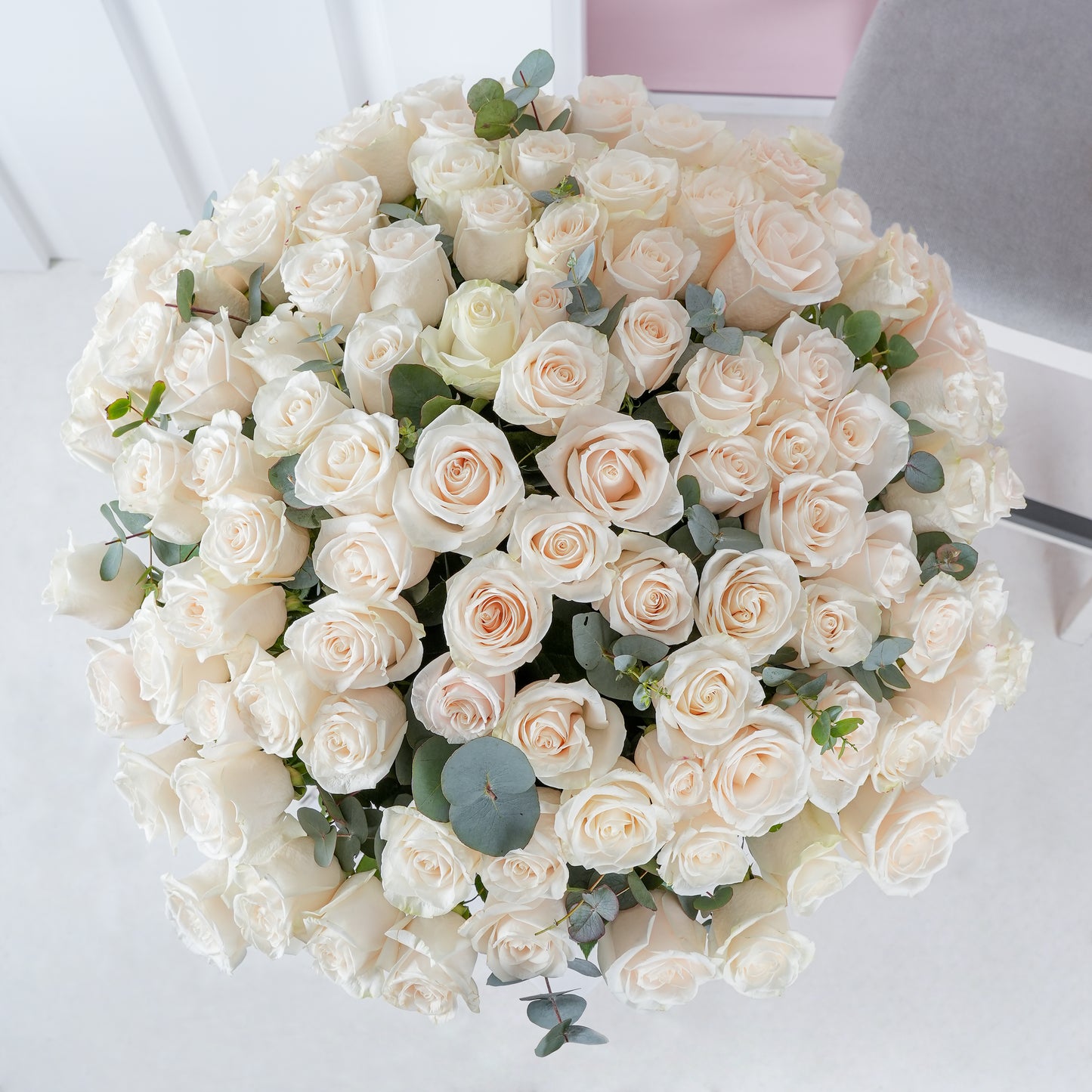 100 white roses in vase arranged with green eucalyptus leaves by Bloom Marbella