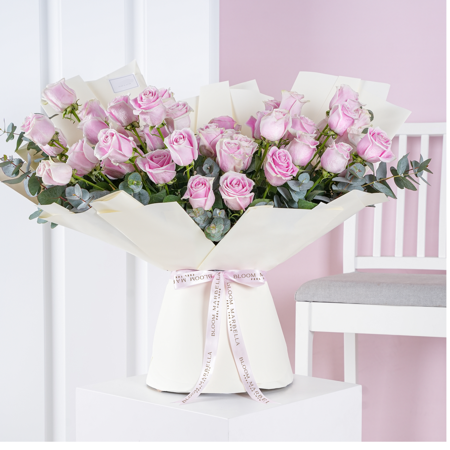 50 pink roses bouquet with eucalyptus leaves wrapped in white paper tied with Bloom Marbella ribbon