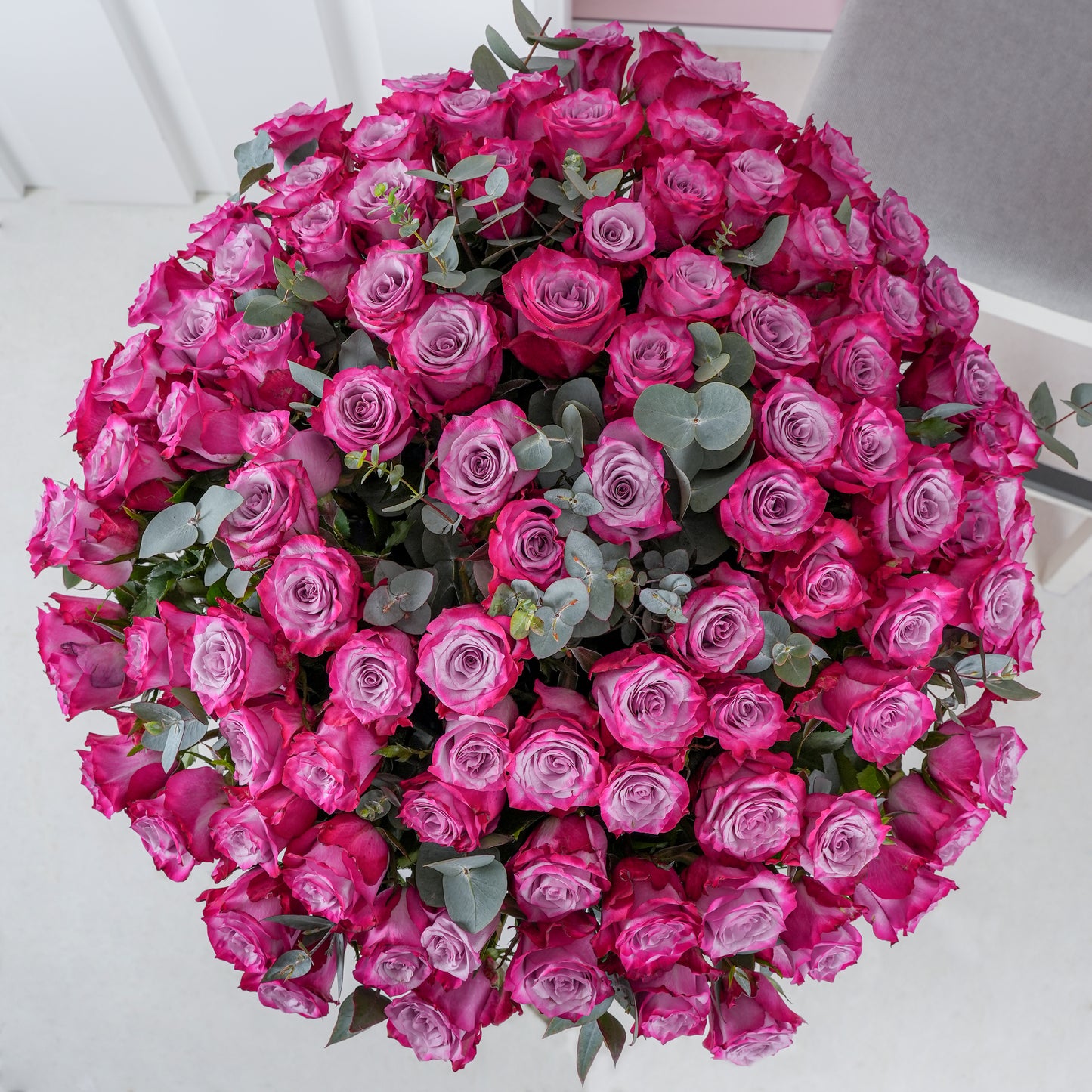 100 purple roses in vase - Bloom Marbella, Spain arranged in a lush bouquet with green eucalyptus leaves
