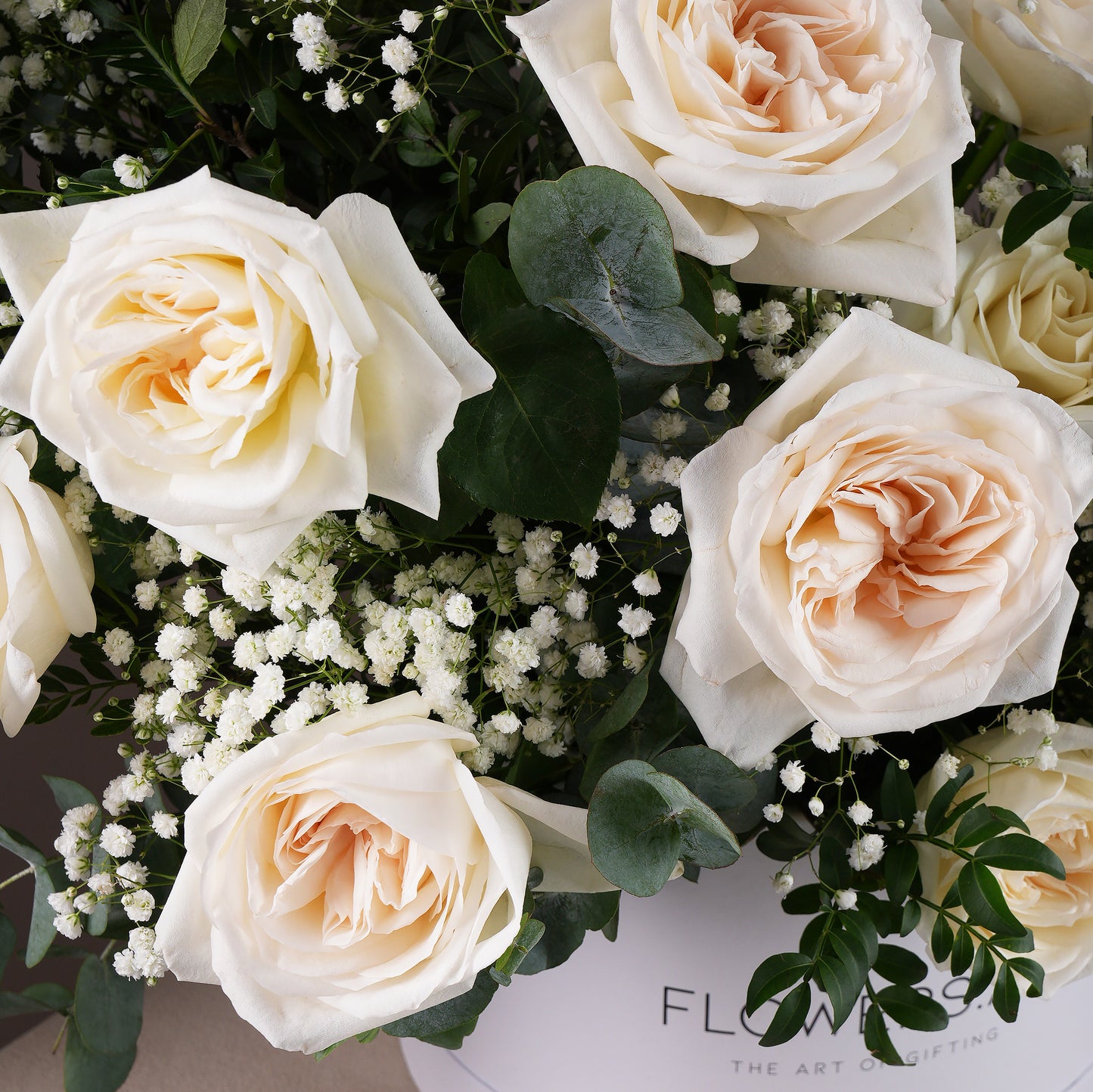 Close-up of white roses and greenery in a white hatbox flower arrangement Bloom Marbella