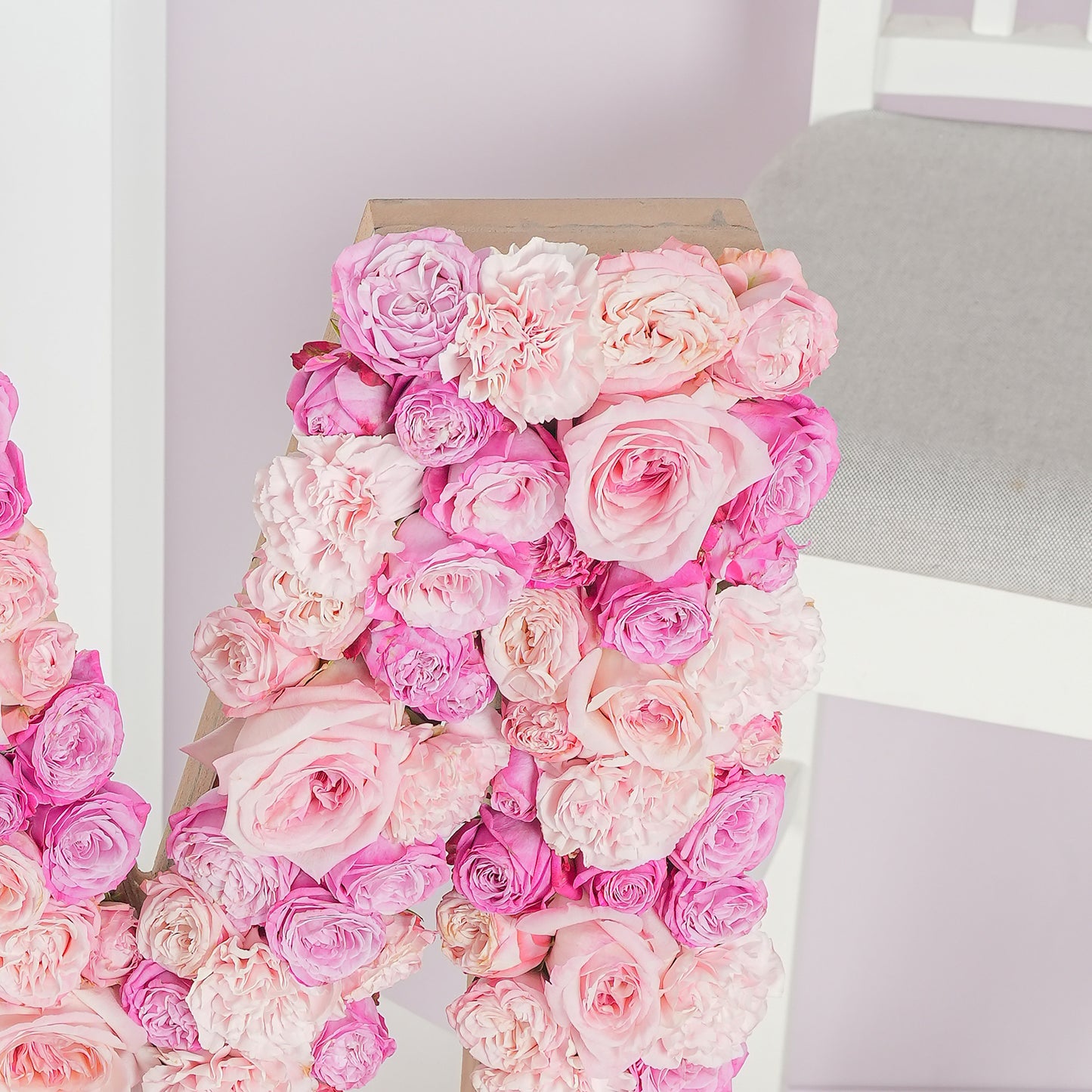 Pink and cream roses arranged in a letter flower arrangement by Bloom Marbella on a chair