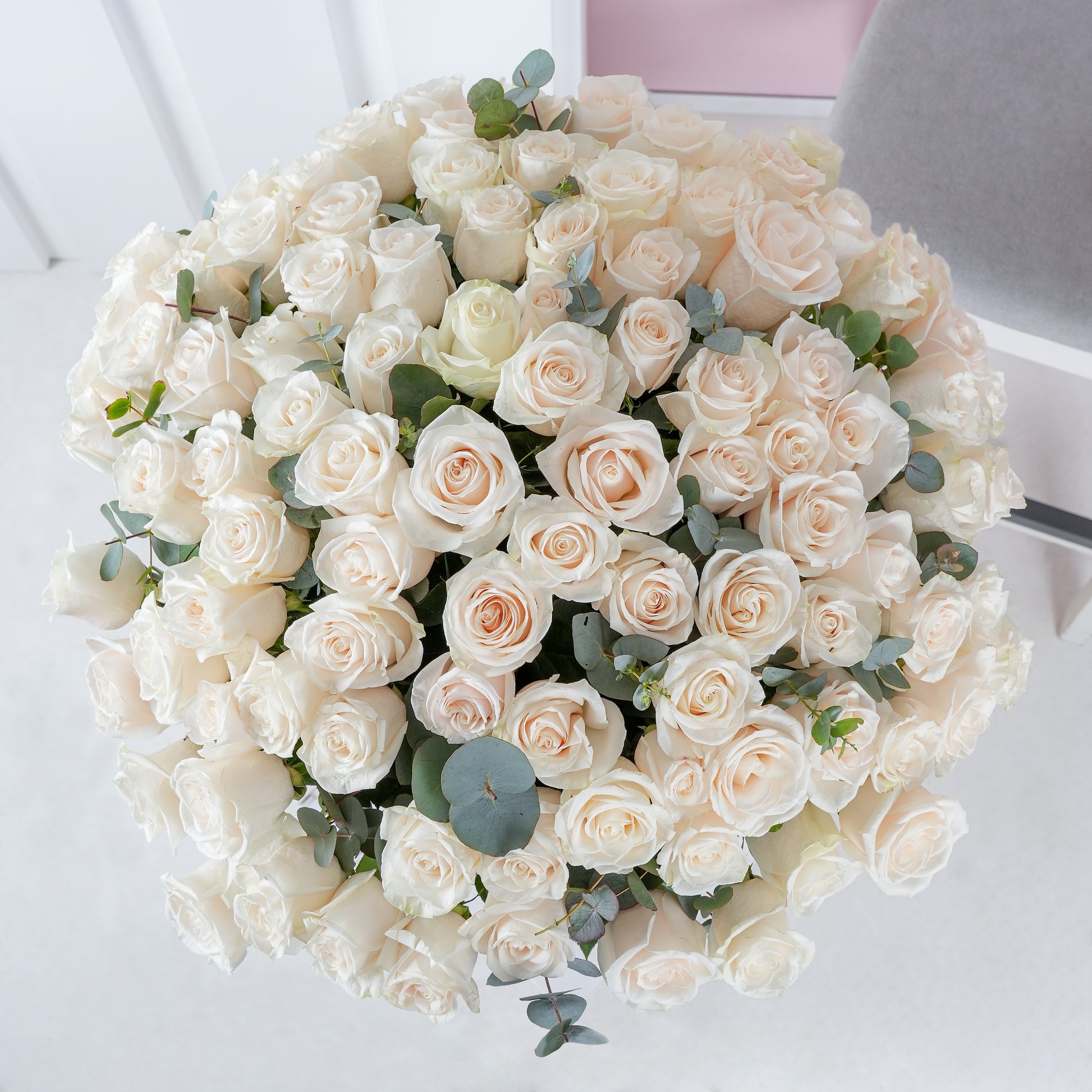 100 white roses in vase arranged with green eucalyptus leaves by Bloom Marbella