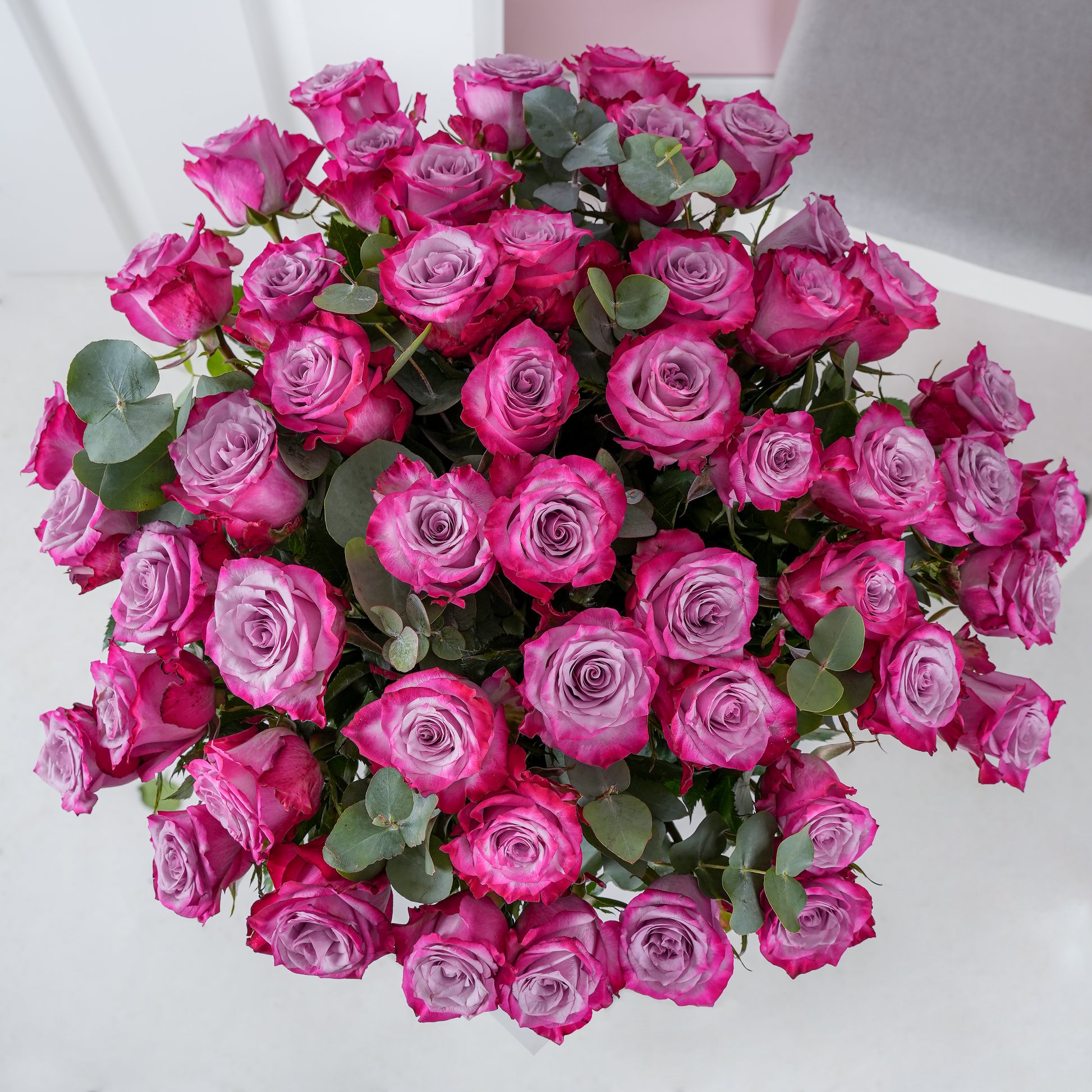 50 purple roses in vase arranged with green leaves by Bloom Marbella on white background