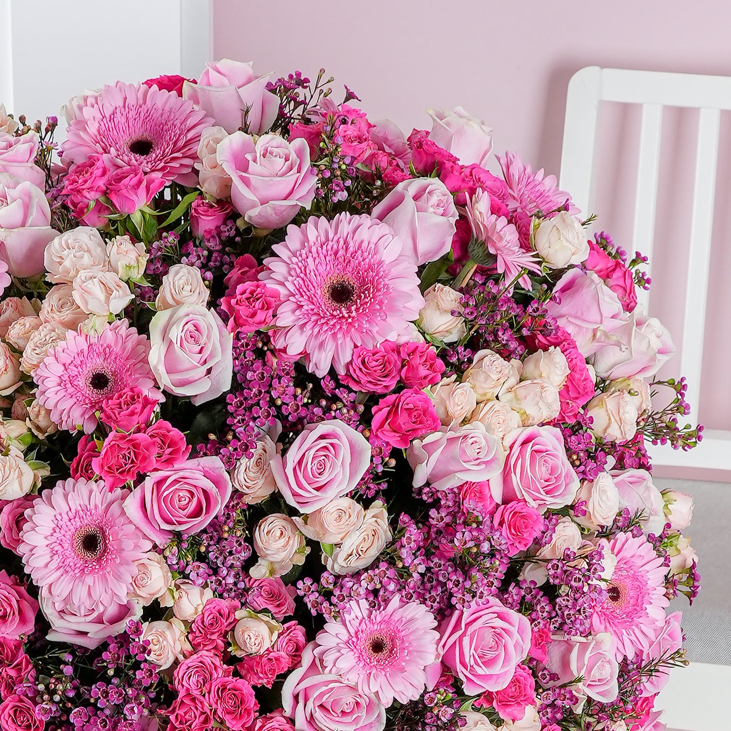 Coraline hatbox flower arrangement with pink gerbera daisies and roses in a vibrant floral display