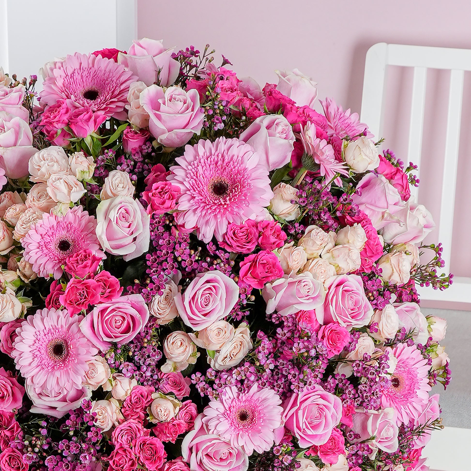 Coraline hatbox flower arrangement with pink gerbera daisies and roses in a vibrant floral display