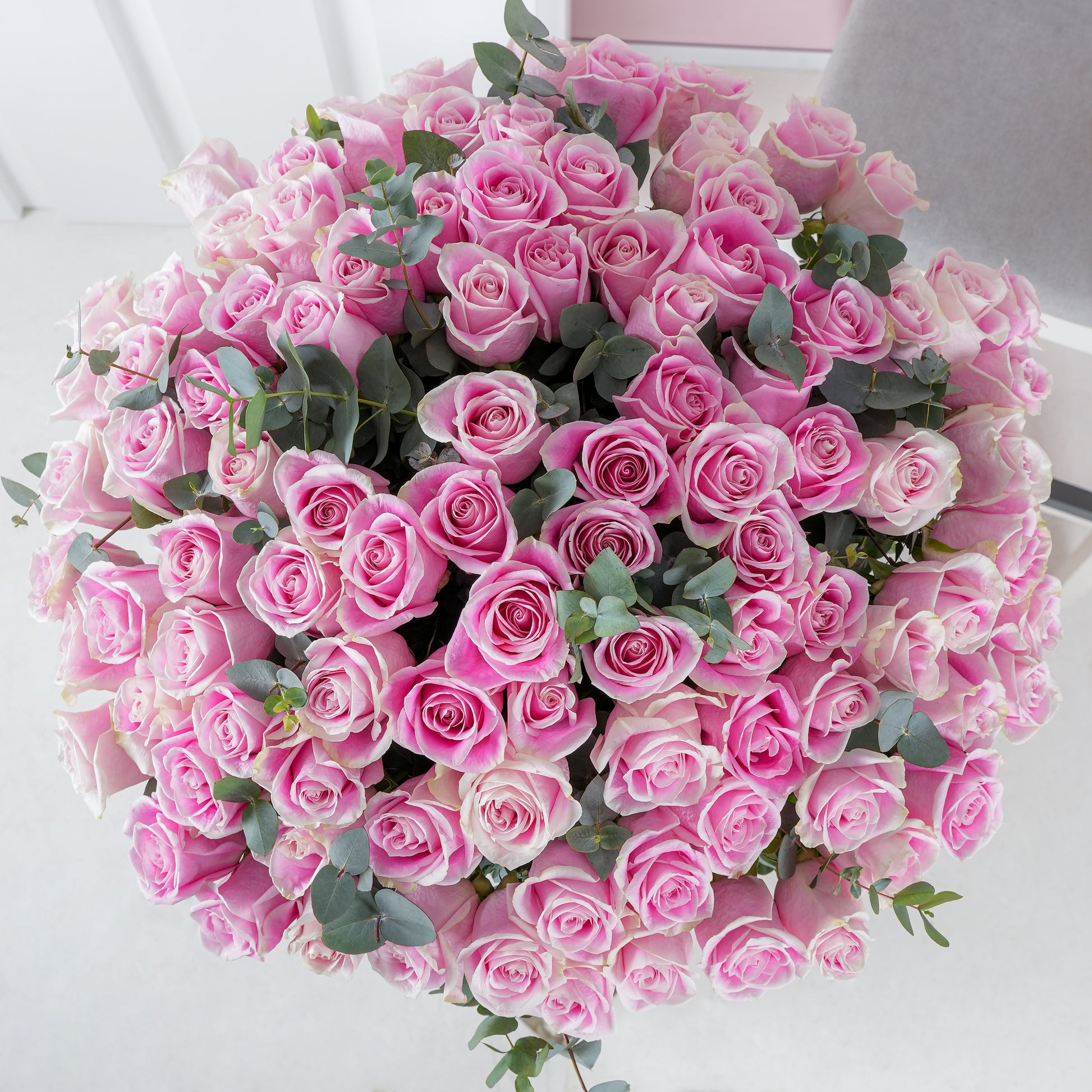 100 pink roses bouquet - Bloom Marbella featuring lush pink roses with green leaves in a large round arrangement