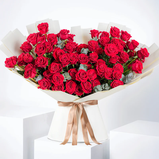 100 red roses bouquet - Bloom Marbella Spain with lush red roses wrapped in white paper and tied with a beige ribbon