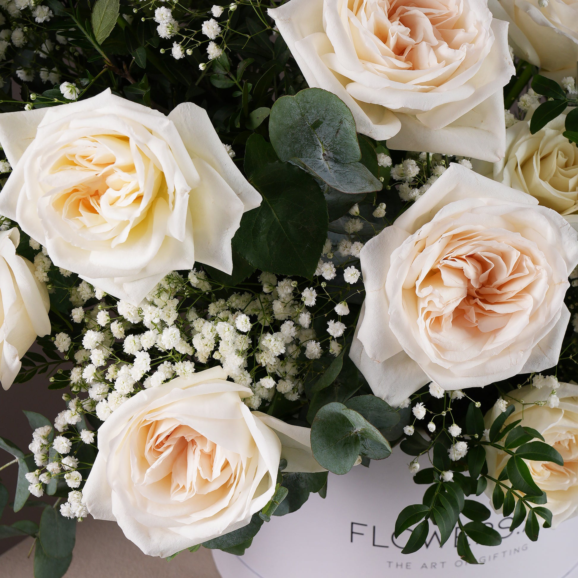 Close-up of white roses and greenery in a white hatbox flower arrangement Bloom Marbella