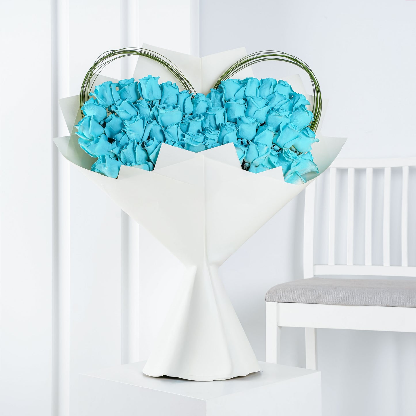 Elegant blue rose bouquet Marbella wrapped in white paper with decorative green stems arranged in a heart shape