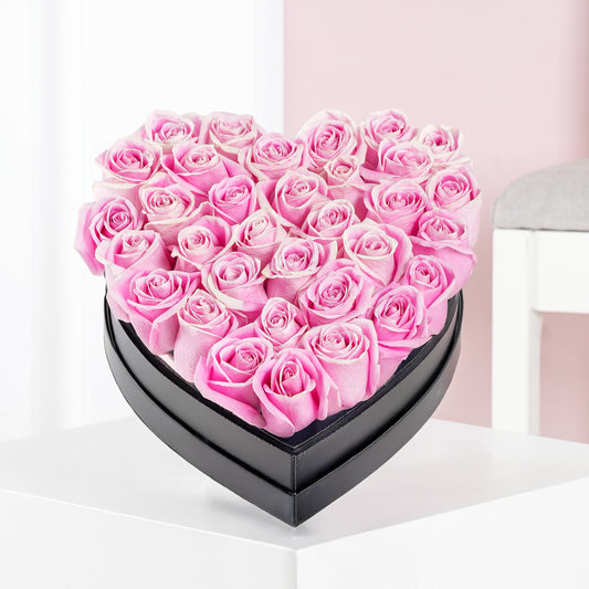 Heart shaped rose arrangement of pink roses in a black box by Bloom Marbella on a white table