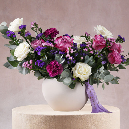 Lavender floral vase arrangement Marbella with white roses and purple flowers in a round white vase by Bloom Marbella