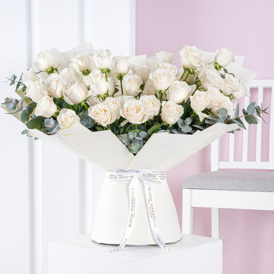 50 white roses bouquet arranged with eucalyptus leaves wrapped in white paper by Bloom Marbella