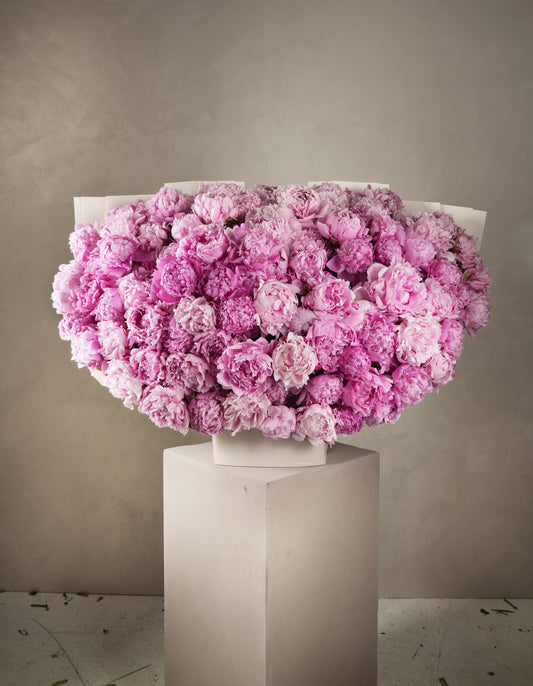 Large pink peony bouquet Marbella by Bloom Marbella displayed on a white pedestal against a neutral background