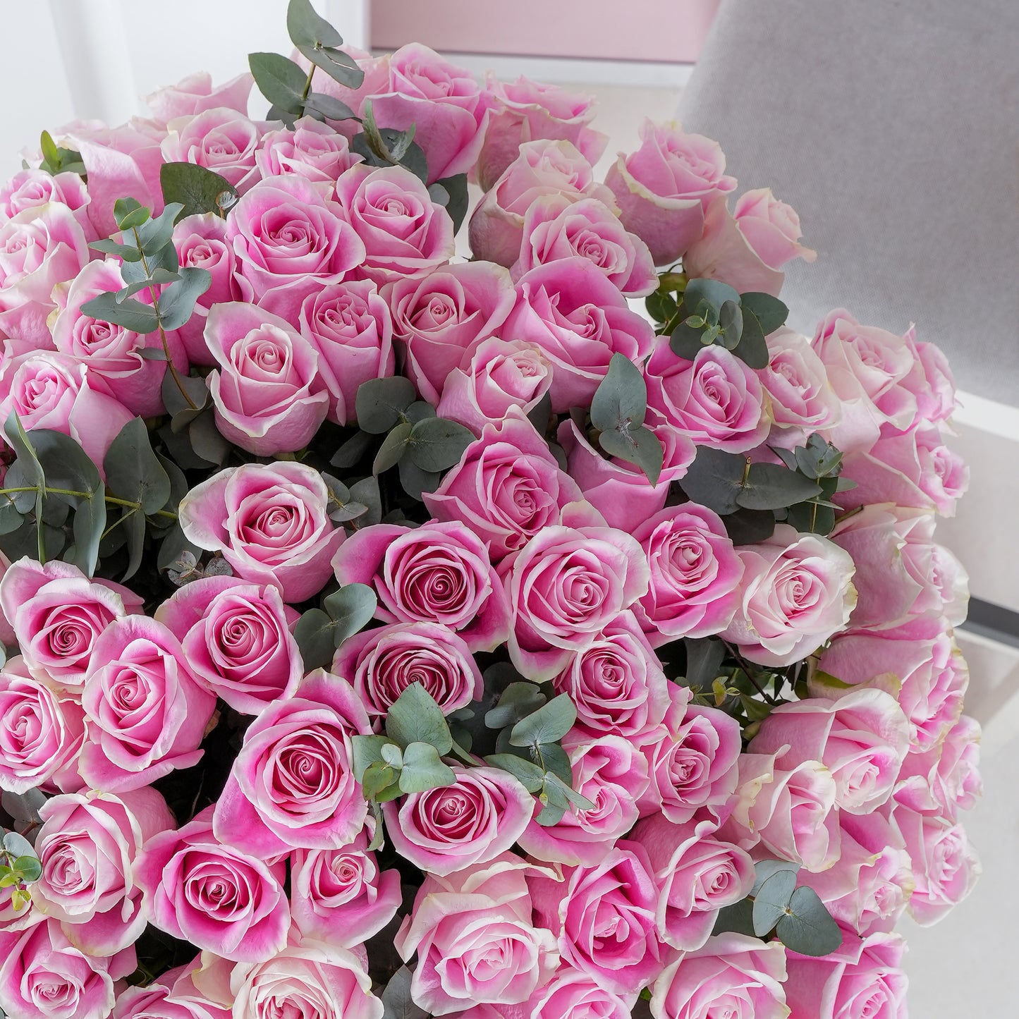 Close-up of a bouquet featuring pink roses vase Marbella with lush green leaves