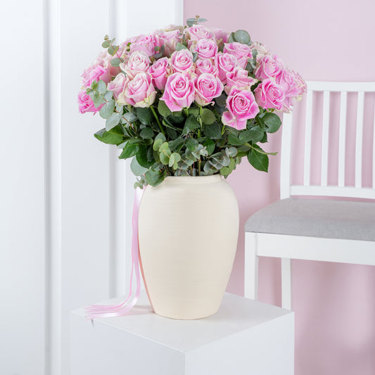 50 pink roses in vase arranged with greenery in a cream ceramic vase by Bloom Marbella