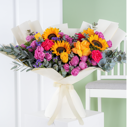 Premium colorful floral arrangement vibrant bloom marbella with sunflowers yellow roses and pink flowers wrapped in white paper