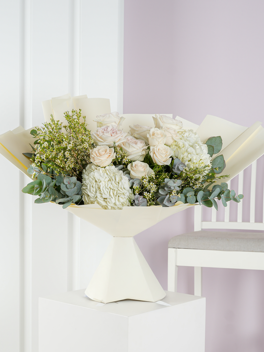 Elegant white flower bouquet Bloom Marbella with roses hydrangeas and greenery in cream wrapping