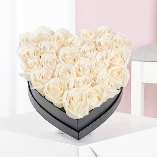 White rose heart arrangement in a black heart-shaped box by Bloom Marbella on a white surface