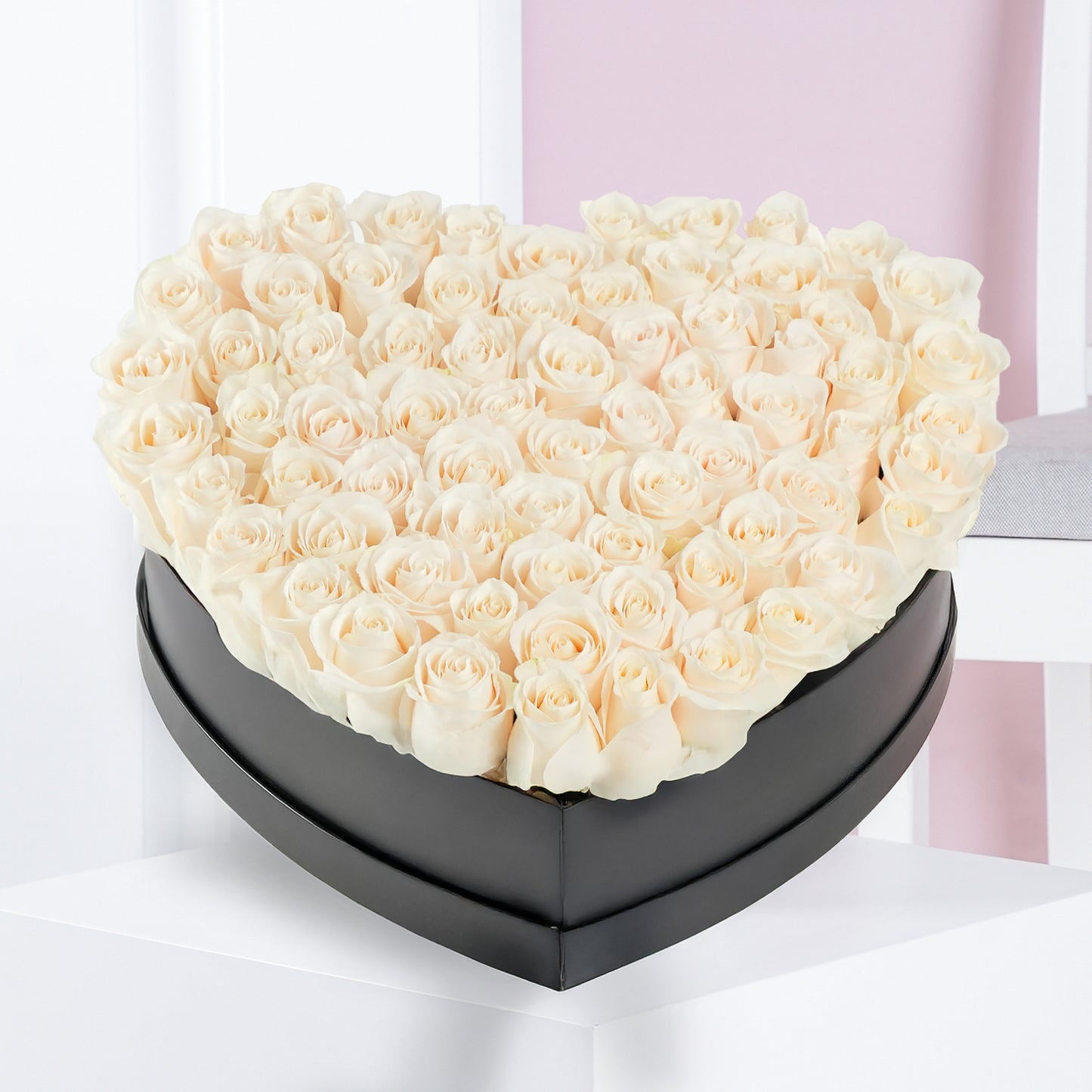 White rose heart arrangement in a black heart-shaped box by Bloom Marbella on white table
